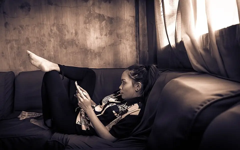 Young woman relaxing on a sofa while playing a game on her smartphone