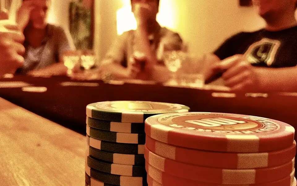 Stacks of red and green poker chips in front of players at a game night