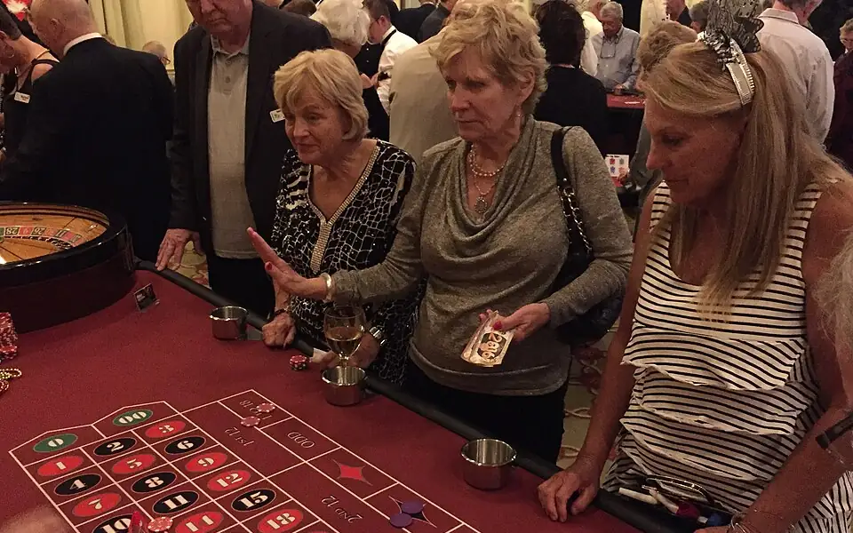 Players leaning over a red betting layout, choosing where to place their chips