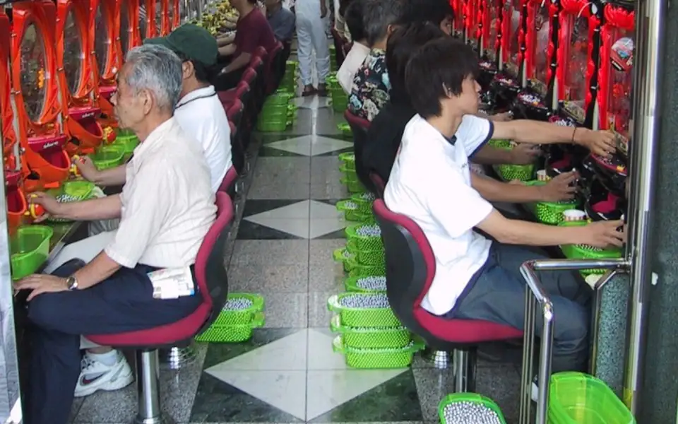 Rows of players seated at bright red machines in a gaming hall